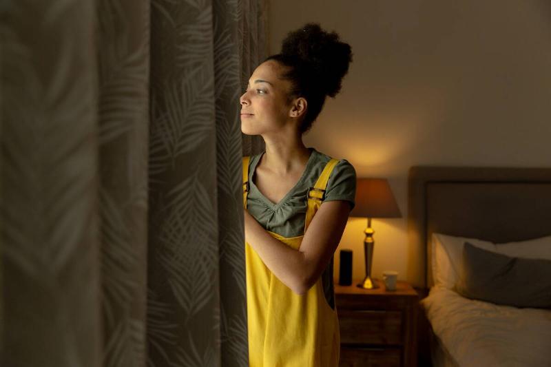 женщина-смешанной расы-стоит-у-окна-и-улыбается-2025-04-03-05-25-46-utc Женщина закрывает шторы ночью.