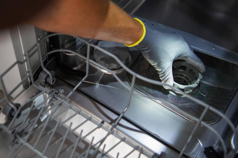 residential-dishwasher-filter-cleaning-2025-03-15-00-27-13-utc A hand reaching into dishwasher to remove the filter.