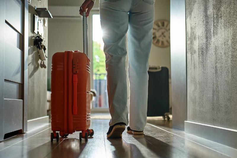 woman-rolls-suitcase-down-hallway-in-apartment-de-2025-08-26-15-34-31-utc Man rolling suitcase back into house.