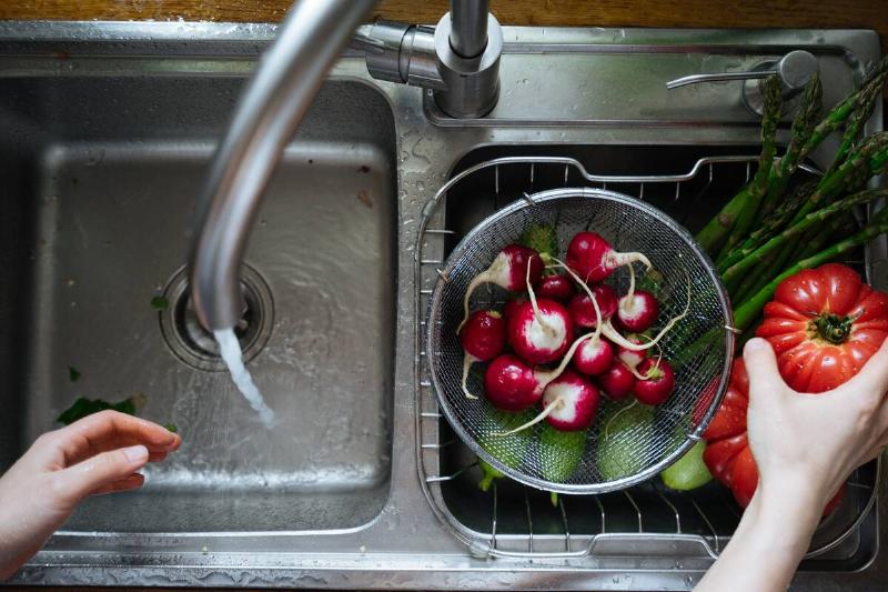 Fruits and veggies being washed in the sink.