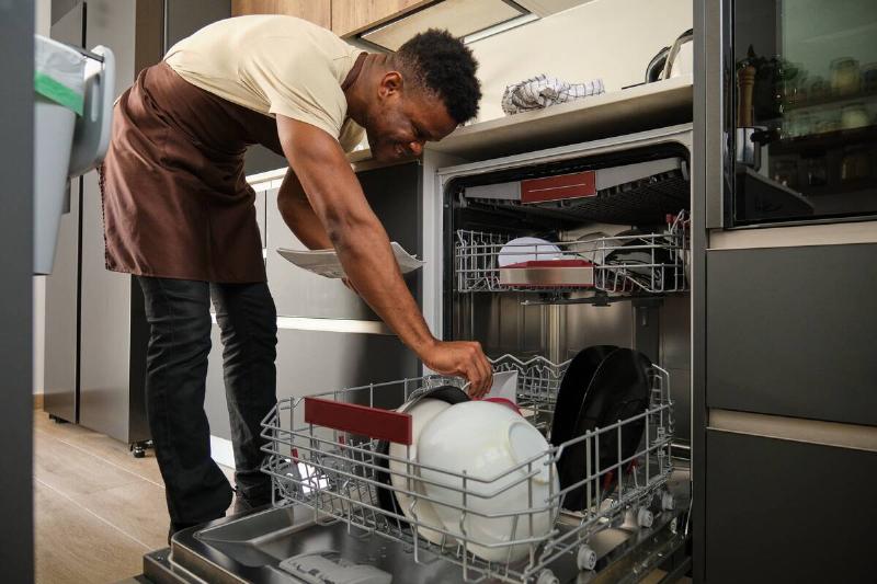A man putting dishes in the dishwasher.