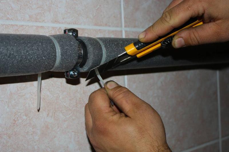 Zip tying a pool noodle on a pipe.