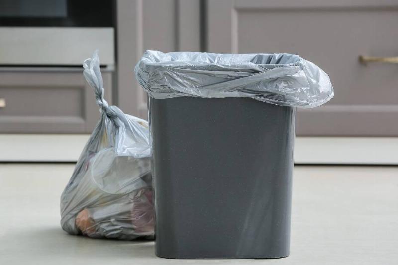 A garbage can that has been emptied with the bag replaced.