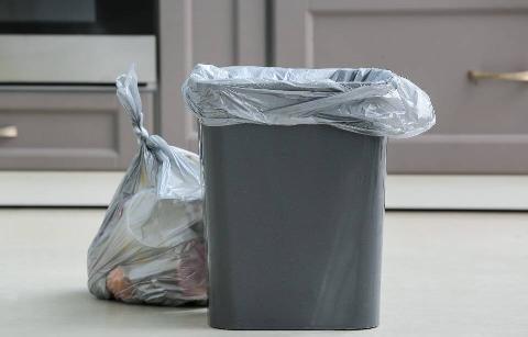 A garbage can that has been emptied with the bag replaced.