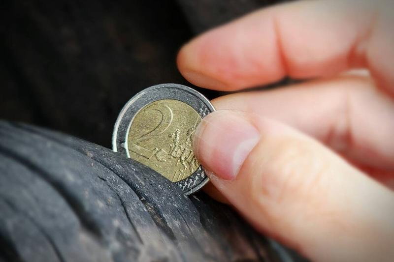 Man using two-Euro coin to check tread depth.