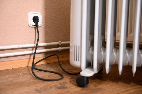 Space heater cord and plug, plugged into a wall outlet. 