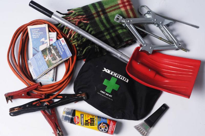 Emergency supplies to keep in a car, including maps, jumper cables, fix a flat, first aid kit, blanket, shovel, jack, and an ice scrapper.