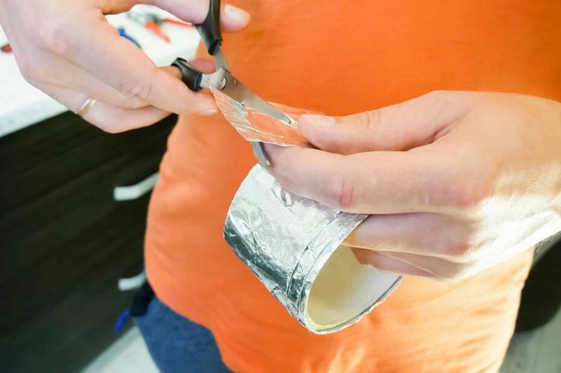 Person cutting foil roll with scissors