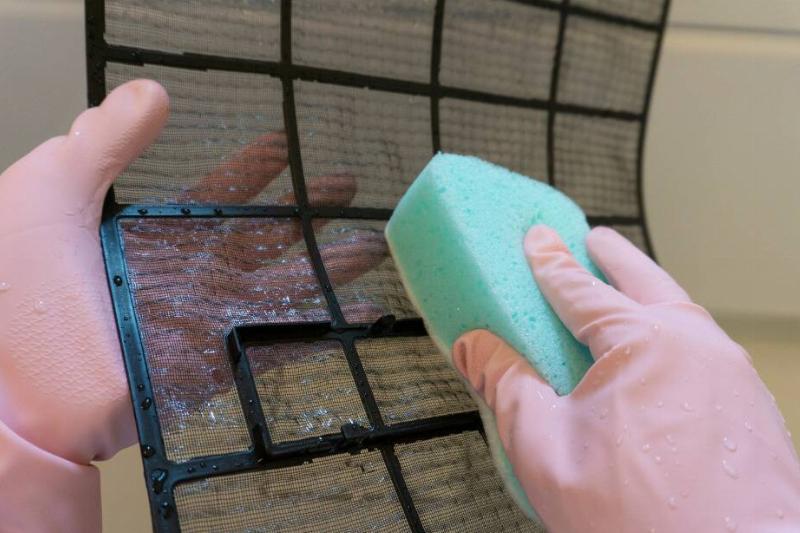 Hand cleaning A/C unit filter. 