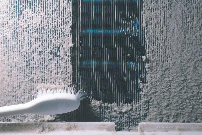 A brush cleaning the coils of an air conditioner. 
