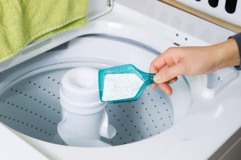 Person putting powder detergent in the washing machine.