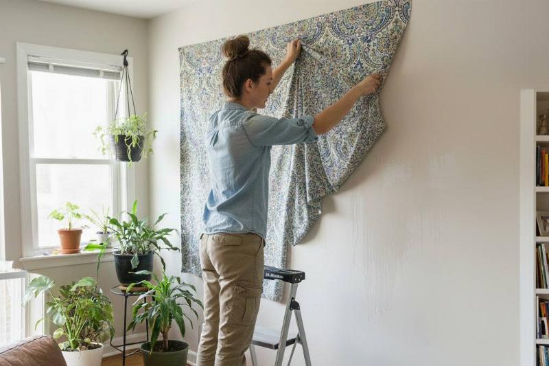 Удаление листа Женщина снимает простыню со стены.