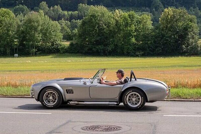 Man driving a Shelby Cobra 427 along a country road