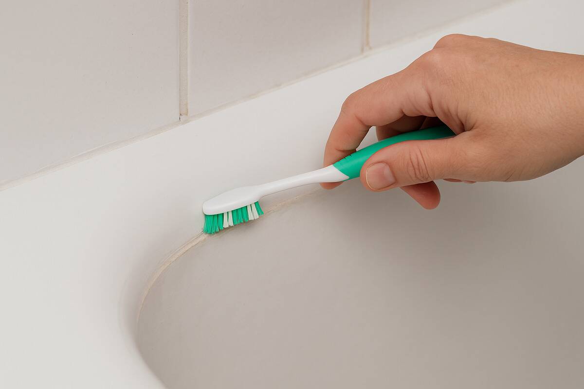 A toothbrush scrubbing away dirt on a bathtub. 