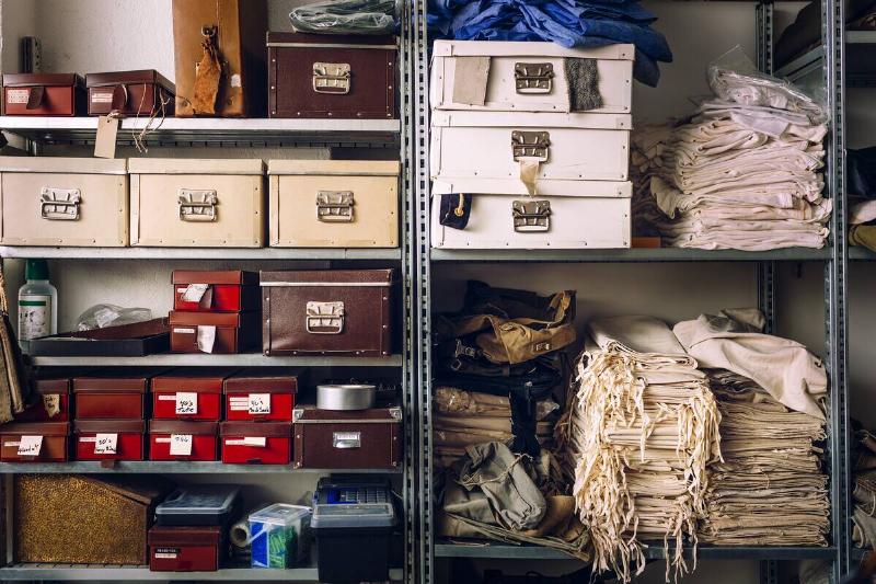 Mismatched storage containers on shelves. 