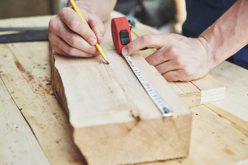 Man marking measurements on a piece of wood. 