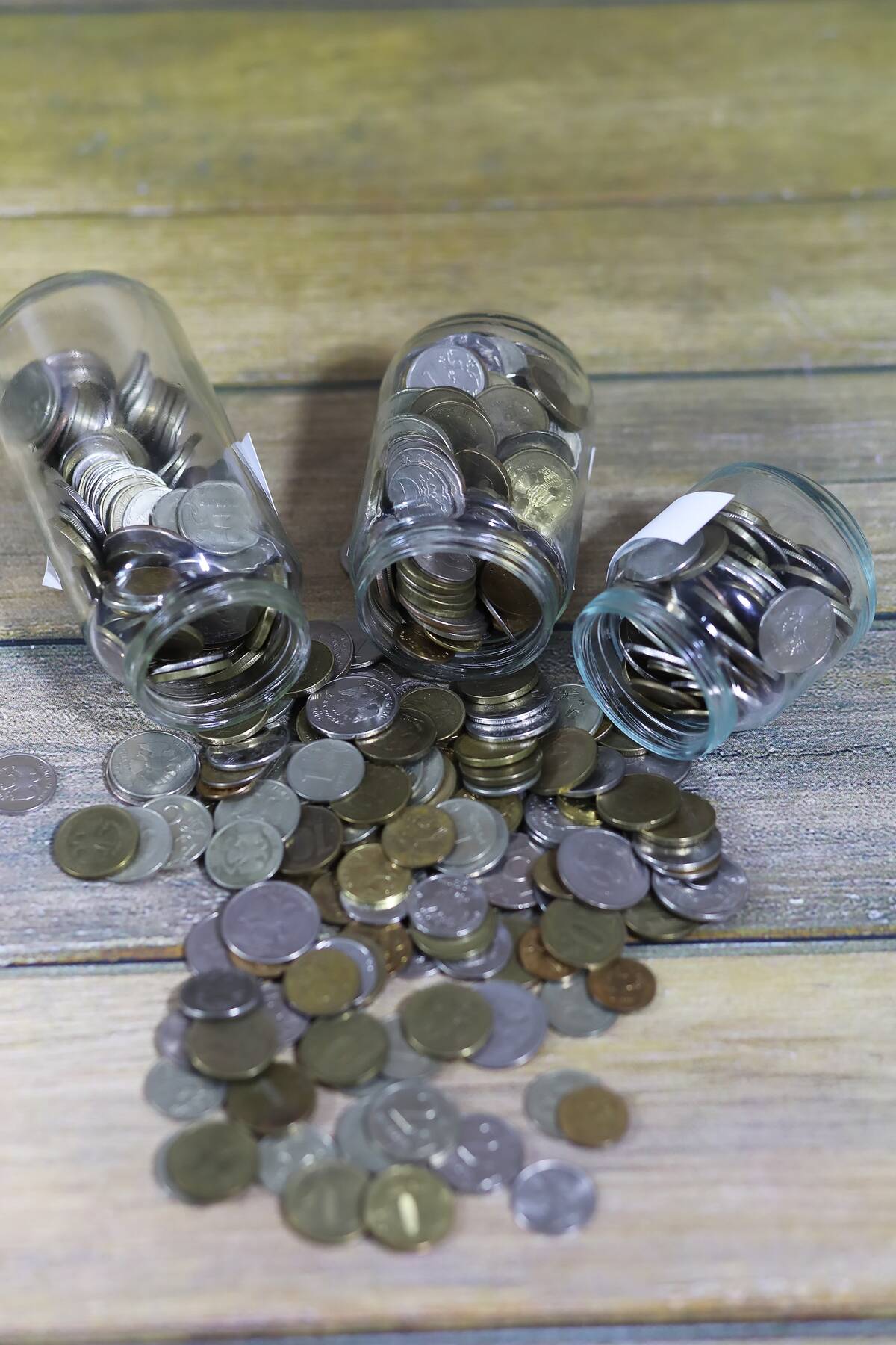 Coins spilling out of three glass jars.