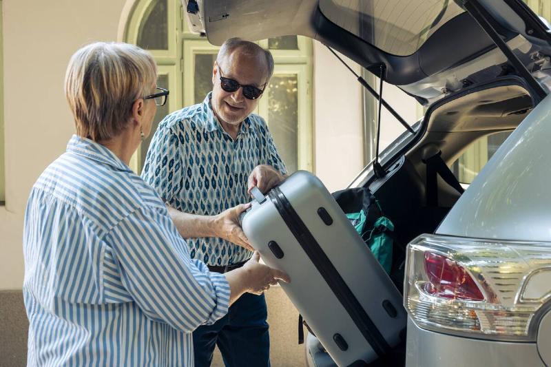 People unloading luggage from the trunk of a car. 