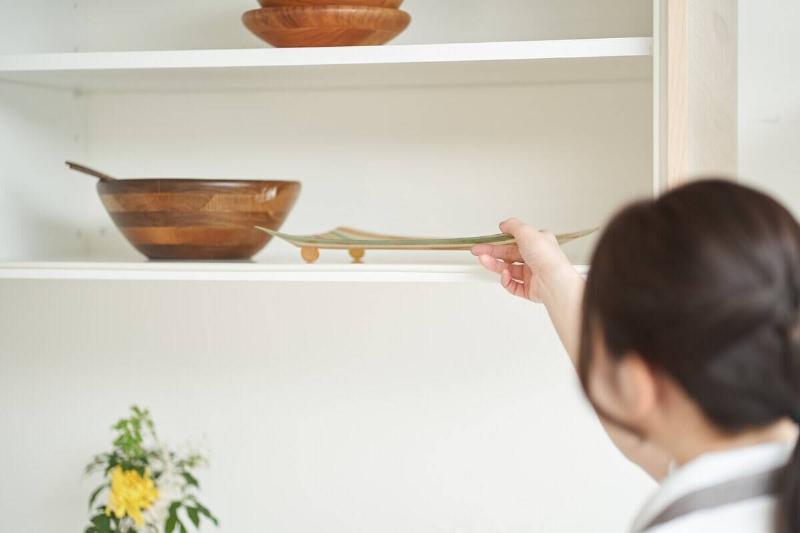 Woman putting a dish on a shelf. 