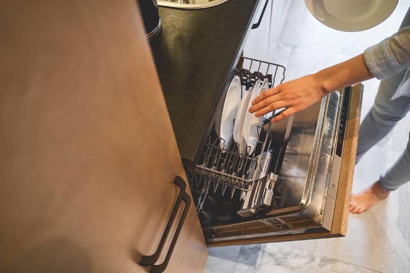 Woman unloading dishwasher.