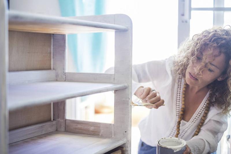 Woman painting old furniture. 