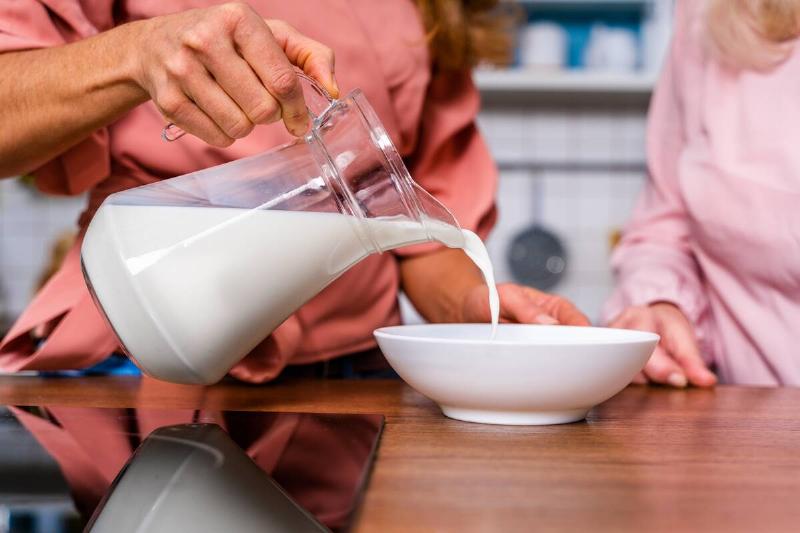 Hands pouring milk into bowl. 
