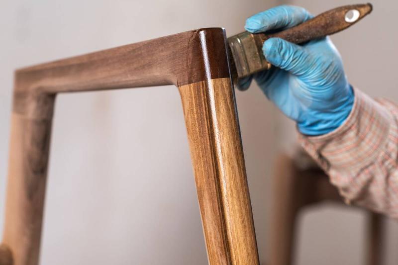 Carpenter applying wood finish to piece 
