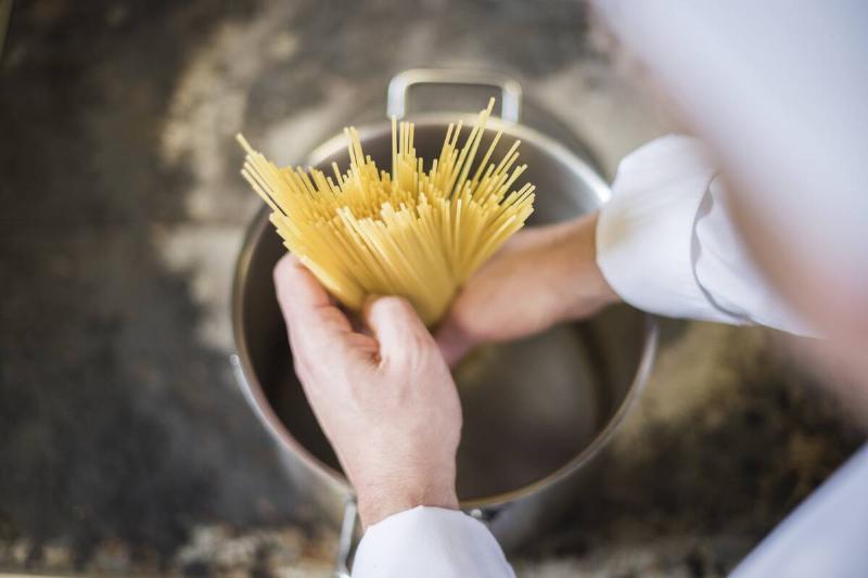 Man putting pasta into water. 