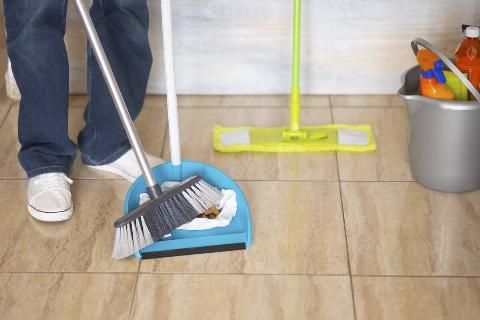 Person sweeping floor with mop close by. 