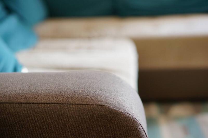 Arm of a couch with fabric upholstery.