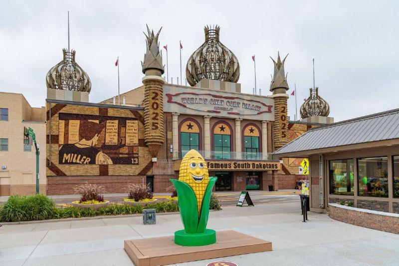 Corn on the Cob statue in front of the exterior of the World's Only Corn Palace in Mitchell, South Dakota, USA
