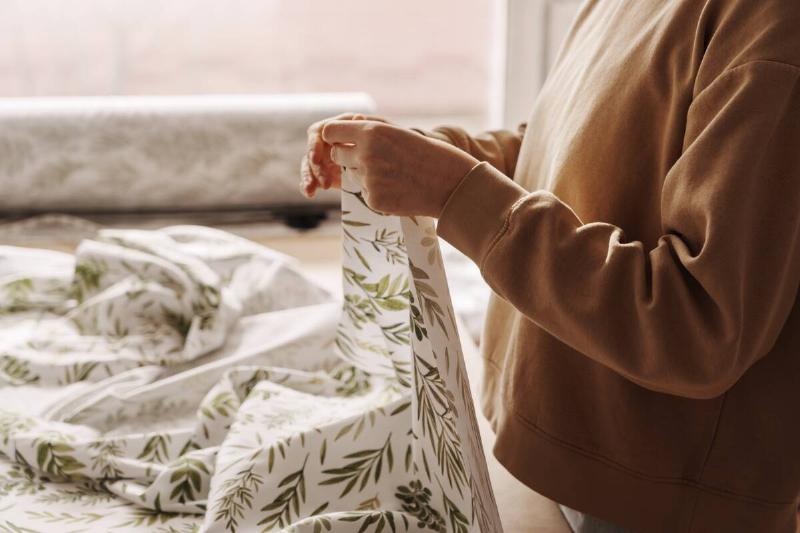 A woman inspecting patterned sheets.