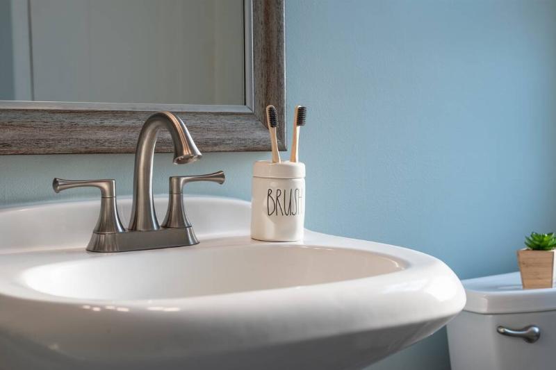 Earth friendly bamboo toothbrushes in a ceramic container on the bathroom sink.