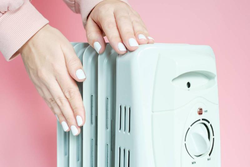 Pressing buttons on electric heater.