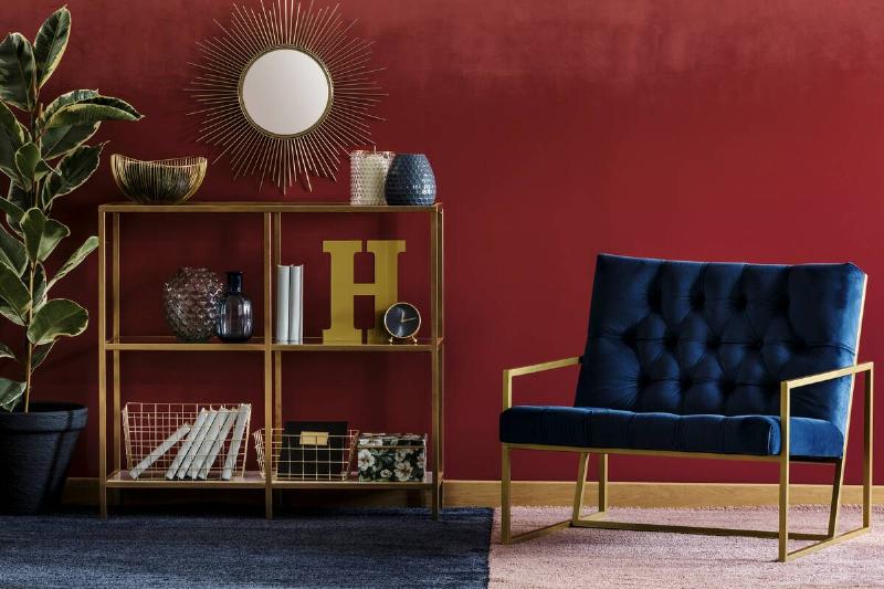 A burgundy wall with blue and gold furniture.