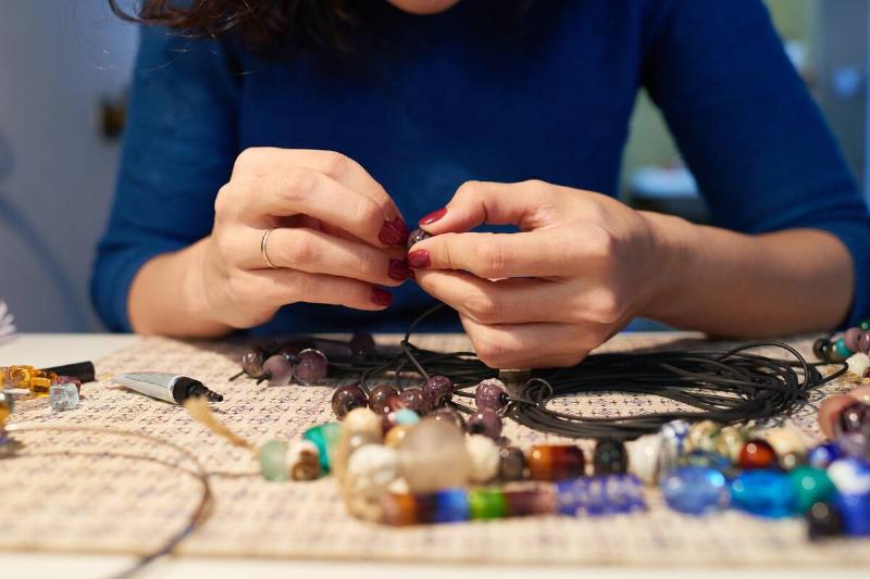 Woman making a necklace with beads.
