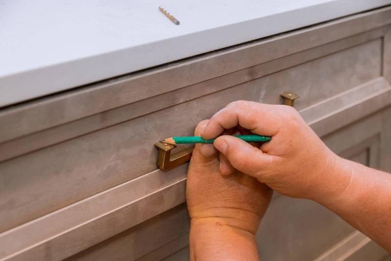 Man applying hardware to finished wood piece. 