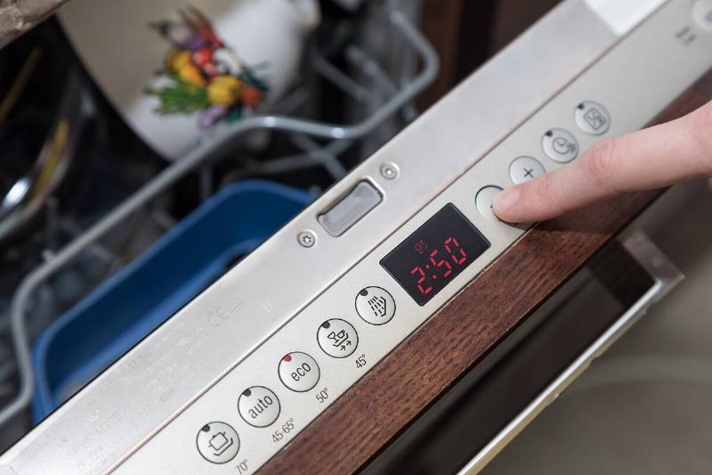 Hands setting settings on dishwasher.
