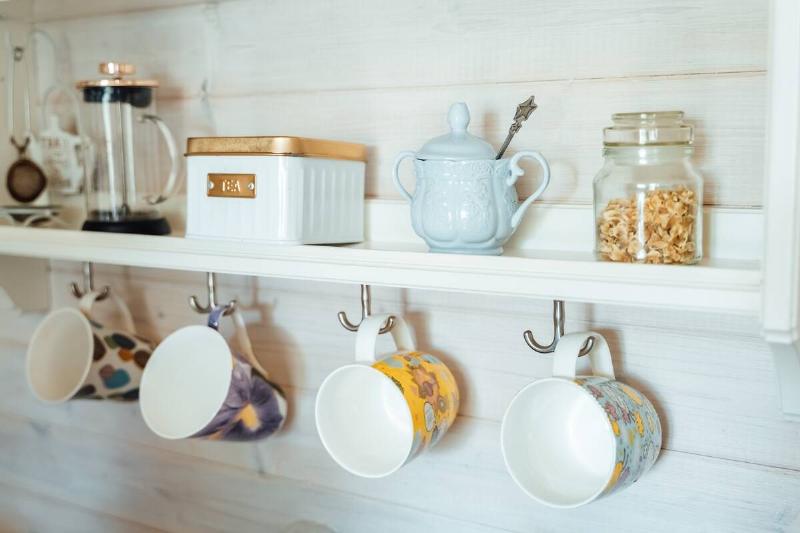 Mugs and tea set on a shelf and hanging hooks.