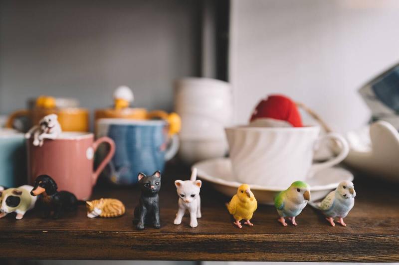 Little animal figurines and porcelain cups on a shelf. 