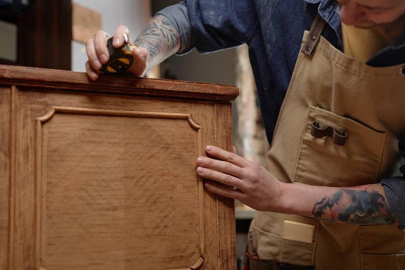 Carpenter inspecting wood piece. 