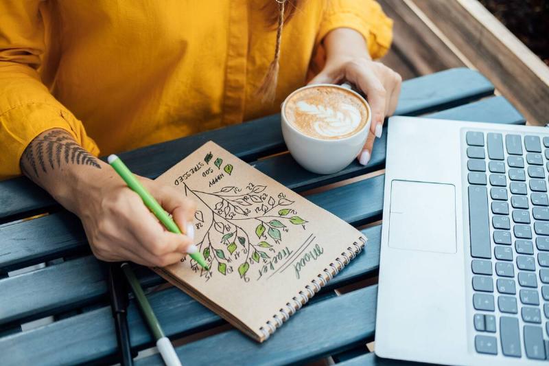 Woman doing bullet journaling at a cafe.