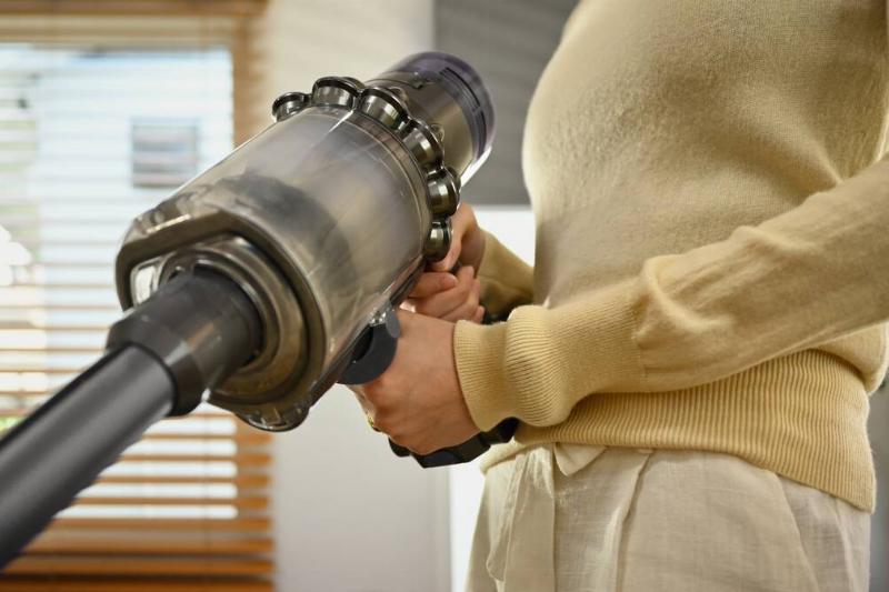 Woman vacuuming and cleaning the dust on her couch.