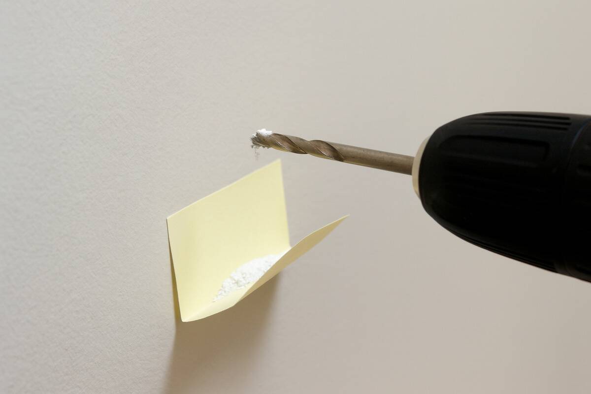 A post-it folded to catch dust under a drill. 