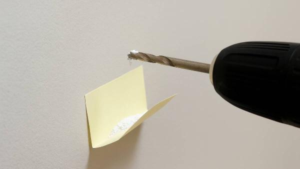 A post-it folded to catch dust under a drill. 