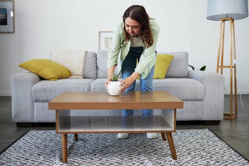 Woman fixing potted plant on coffee table. 