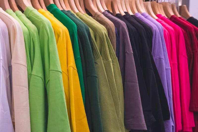 Row of colorful shirts hanging on hangers. 