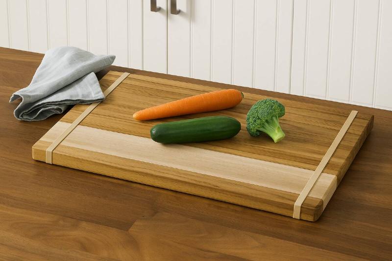 A cutting board with vegetables and rubber bands around both ends. 