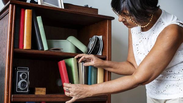Woman cleaning bookshelf.