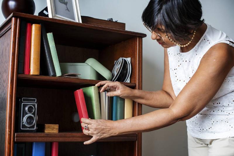 Woman cleaning bookshelf.